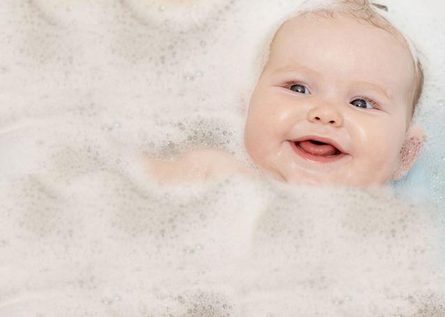 bebé recién nacido sonriendo en la hora de baño